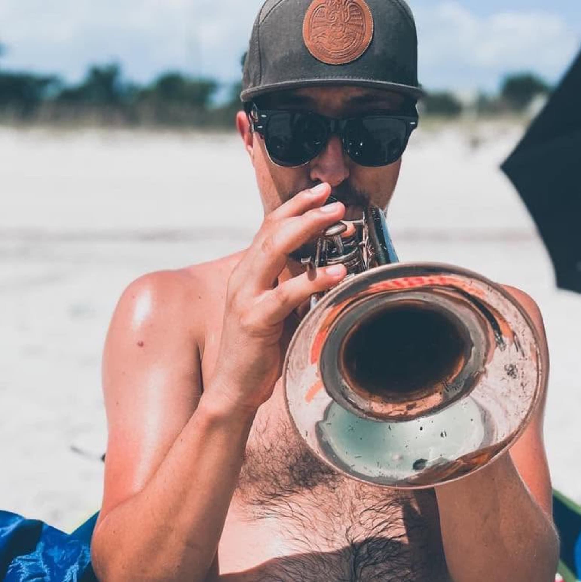 Reid Poole playing trumpet outdoors in sunglasses