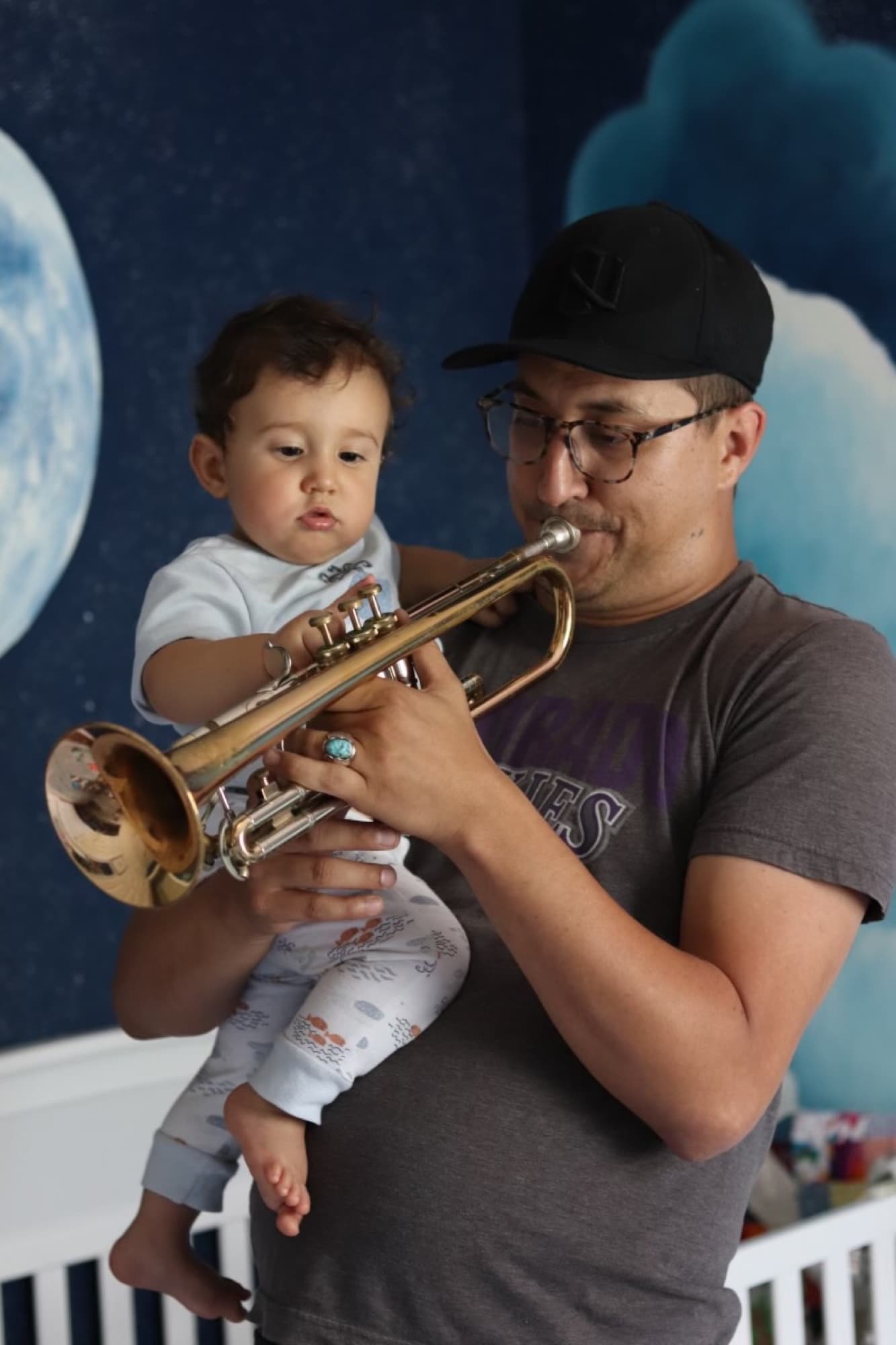 Reid Poole holding a child while playing trumpet