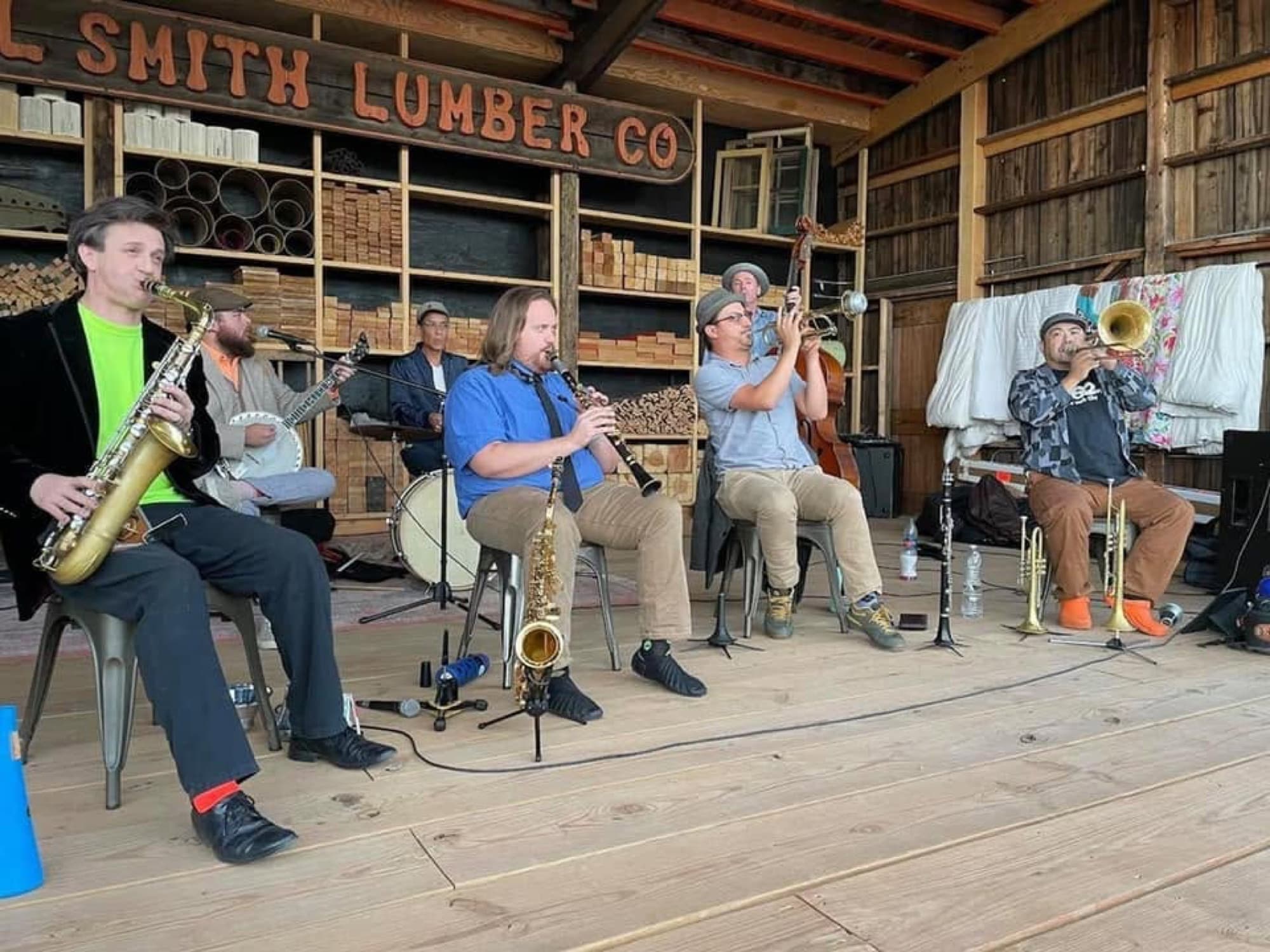 A seated jazz ensemble performing on a wooden stage